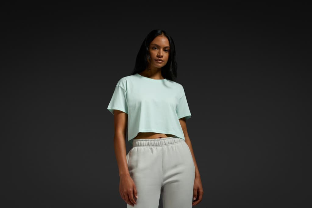 Model in a mint AS Colour crop tee and grey track pants.