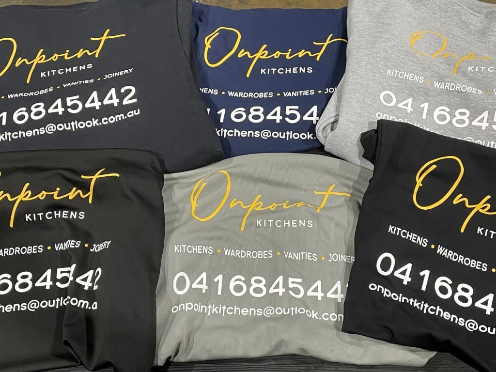 Assorted shirt colours showing yellow and white screen-printed Onpoint Kitchens branding and contact details.